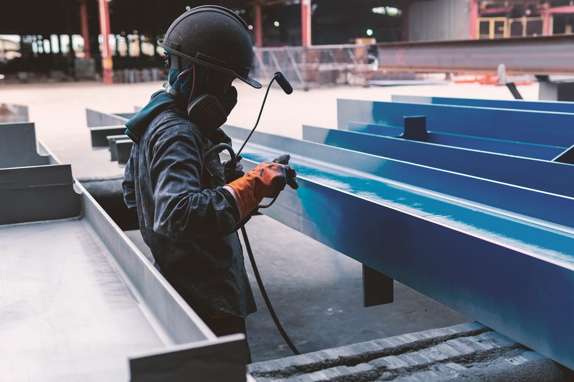 Application de peinture industrielle par projection sur une structure métallique.